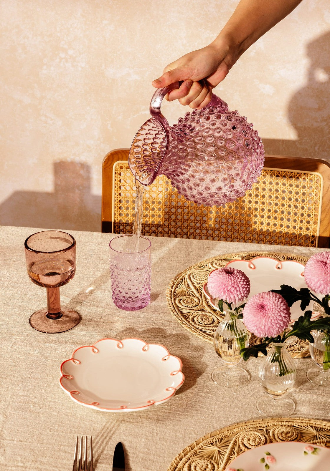 A translucent pink glass pitcher with a textured bubble surface and curved handle from eleanor wine glass violet collection