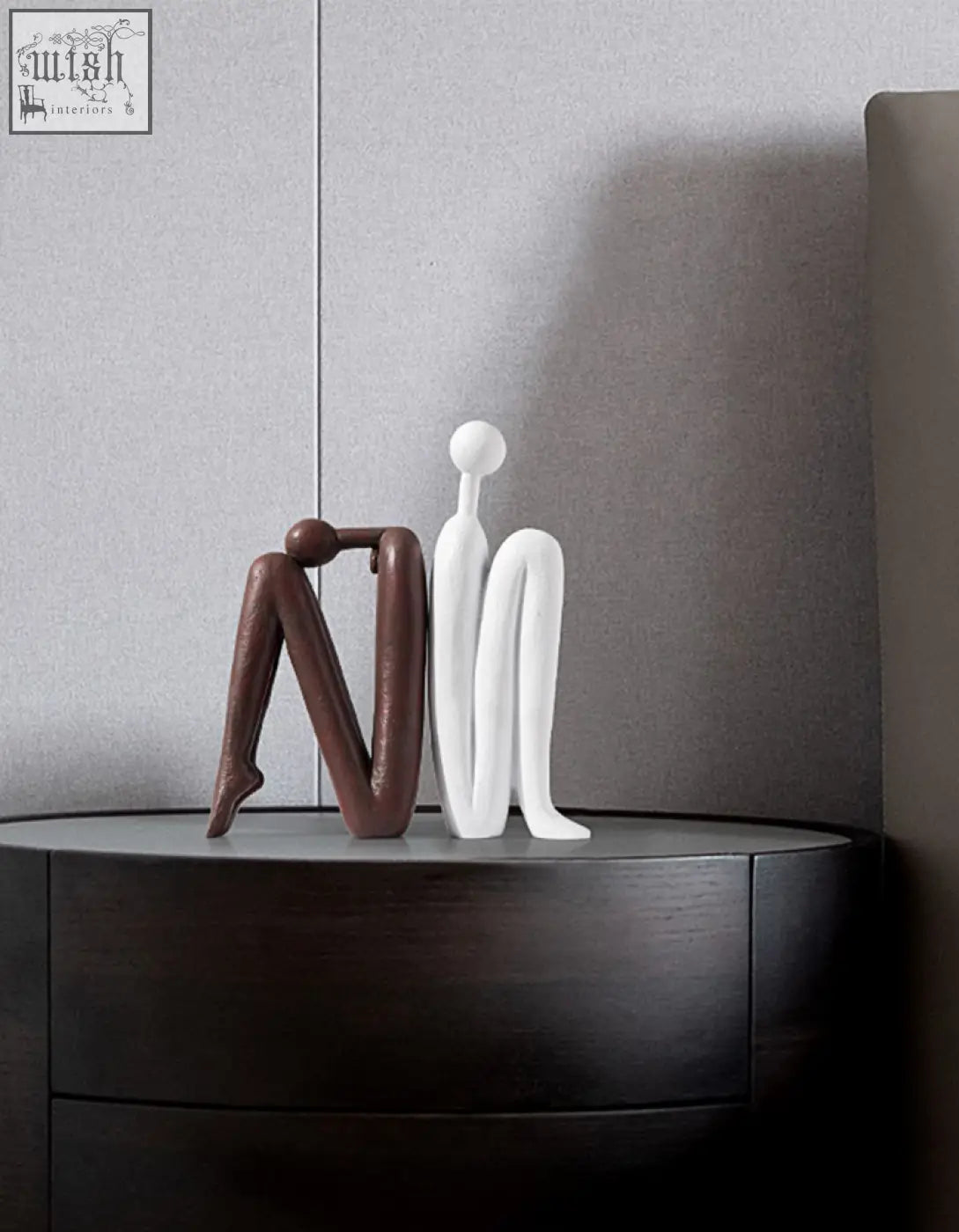 Two minimalist resin Eleni bookends in matte brown and glossy white sit side by side on a dark wooden shelf decorative surface