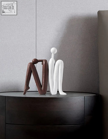 Two minimalist resin Eleni bookends in matte brown and glossy white sit side by side on a dark wooden shelf decorative surface