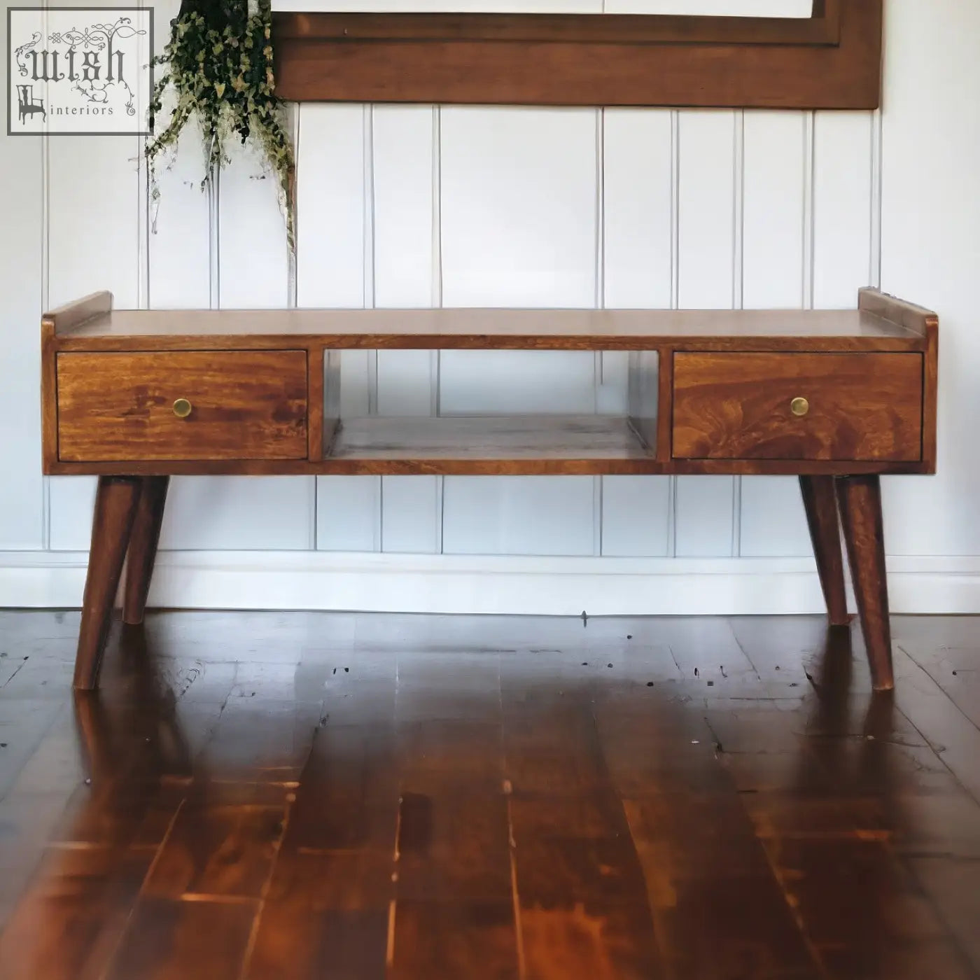 A mid-century modern solid mango wood console table with two drawers, glass shelf, tapered legs, and brass knobs