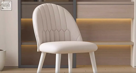 A sleek white upholstered chair with tufted back and slender legs beside the elmer office desk with sintered stone top