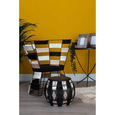 Black and white geometric patterned woven chair with modern angular design next to elm wood large side table with brass-finished iron legs