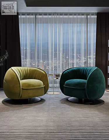 Two plush velvet swivel lounge chairs in olive green and deep teal on a striped rug by floor-to-ceiling windows