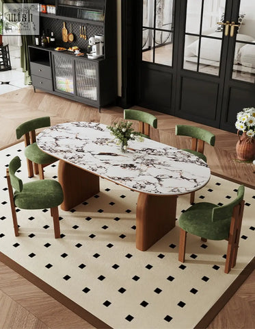 Elegant emerson dining table with white marble top featuring black veining and wooden legs surrounded by green velvet chairs