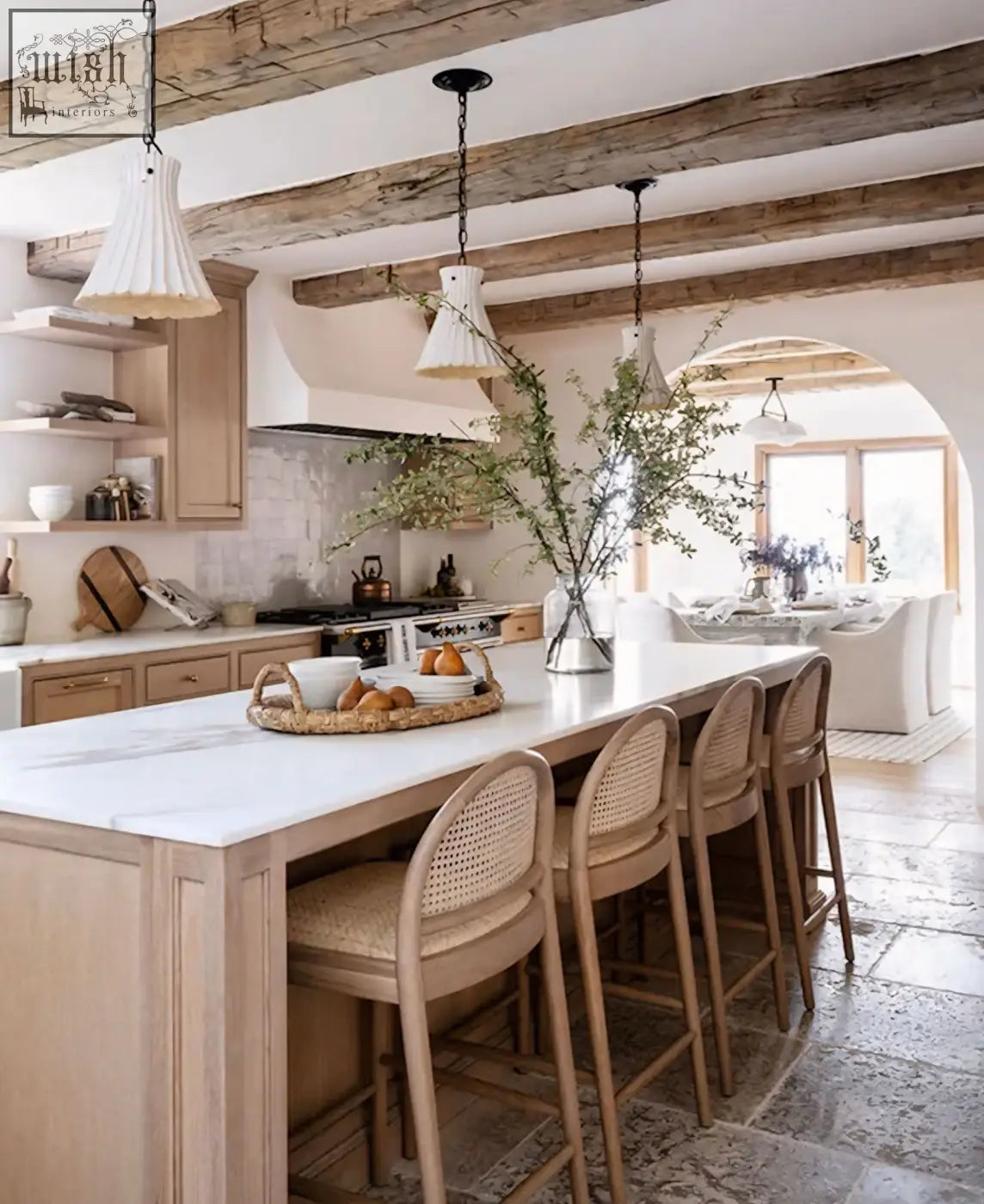 White marble kitchen island with light wood cabinetry and woven cane emi bar stools at the counter