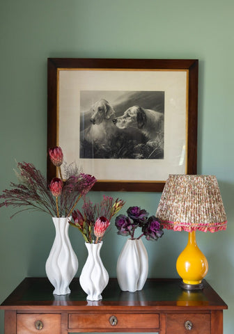 Three white ceramic vases with wavy twisted designs holding dried flowers and proteas in emilie vase style