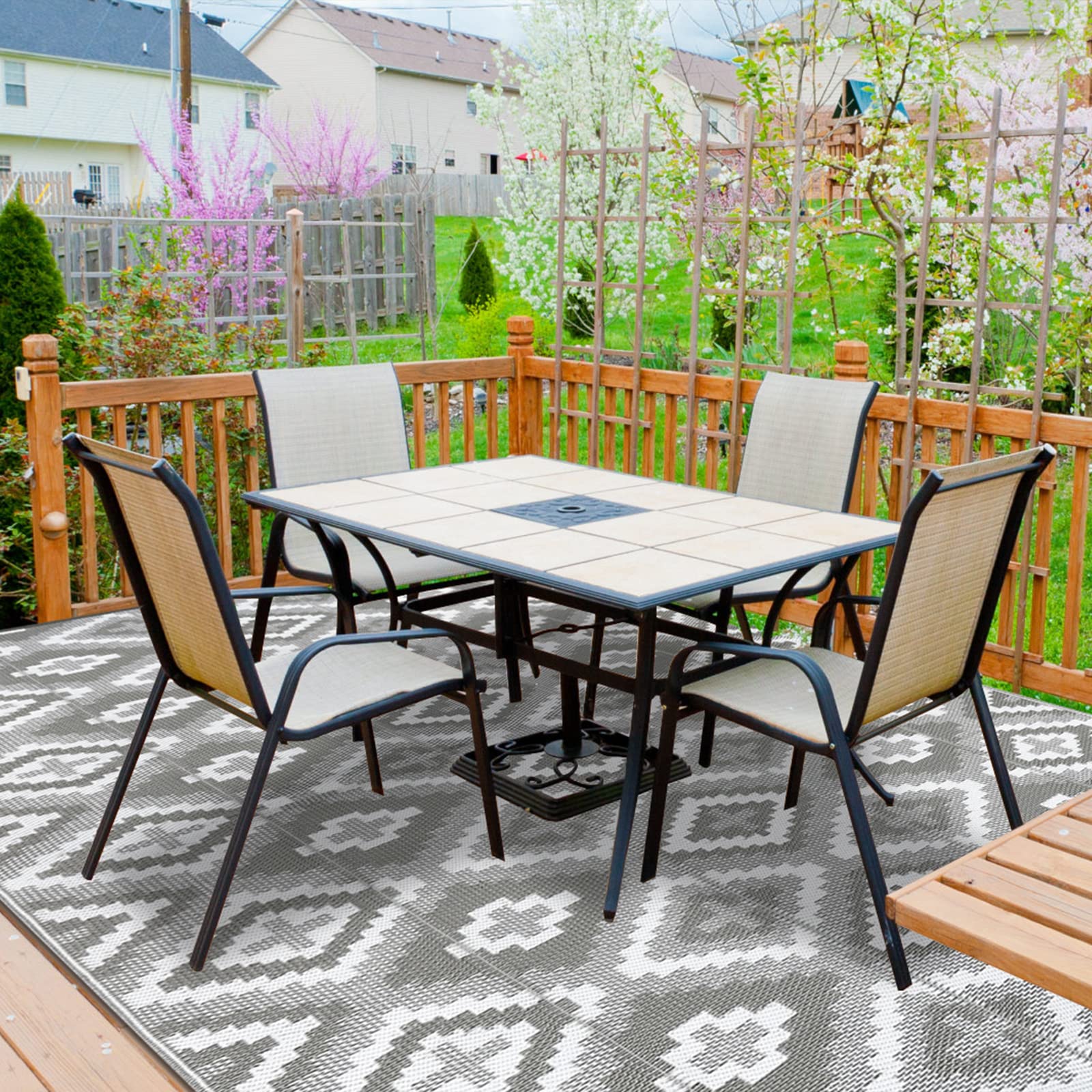 Black metal patio table with tiled top and dark square inset shown with enyhom large outdoor reversible woven outdoor rug