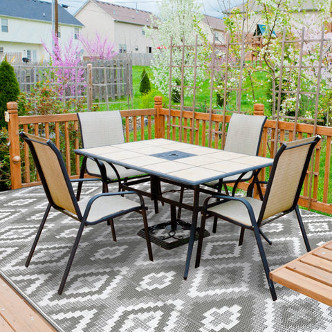 Black metal patio table with tiled top and dark square inset shown with enyhom large outdoor reversible woven outdoor rug