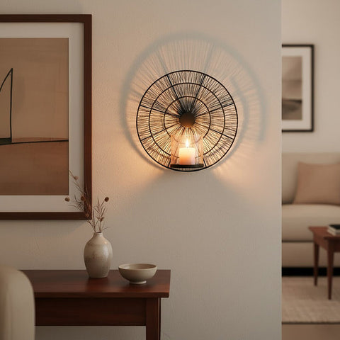 Enzo black wire wall sconce with circular metal frame and radial wire design holding a lit white candle