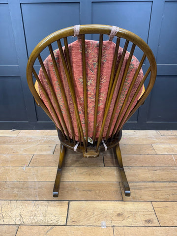 Vintage ercol grandfather rocking chair model 315 with curved wooden frame and reddish-pink patterned cushions