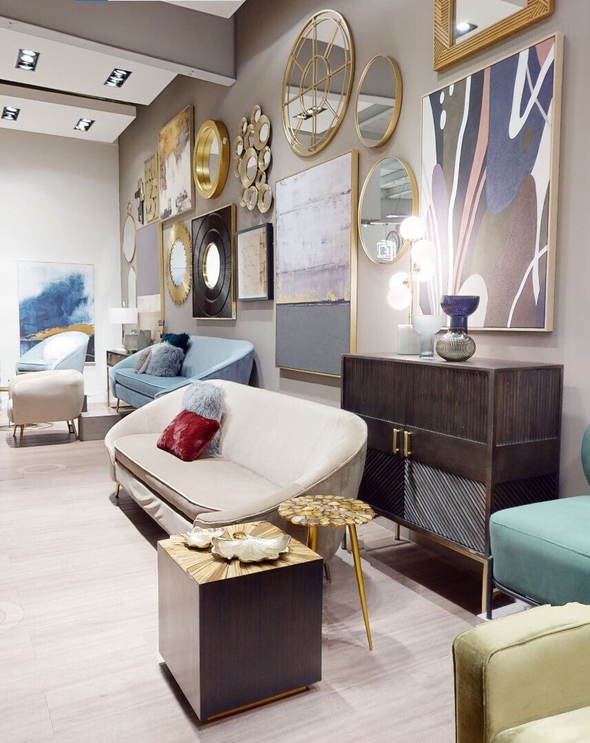 Cream-colored sofa with sleek modern design and gold legs next to a small light blue glass vase for decor