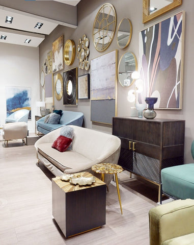 Cream-colored sofa with sleek modern design and gold legs next to a small light blue glass vase for decor