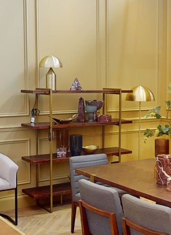 A modern open shelving unit with dark wood finish and gold frame displaying a small light blue glass vase and decor items