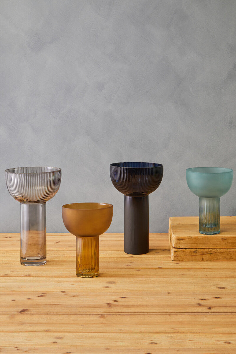 Set of four small light blue glass vases with ribbed texture and slender stems in gradient hues perfect for decor