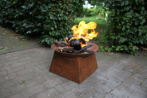 Rusty metal fire pit with square base and round top filled with burning logs esschert design rust fire bowl white