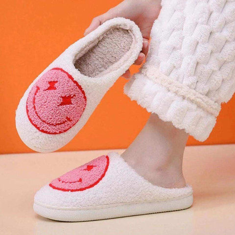 White fuzzy euphoria slippers with a pink embroidered smiley face design perfect to stay warm and cozy