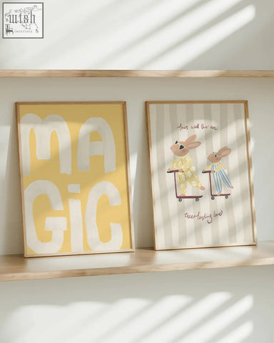 Two framed art prints on a wooden shelf featuring a rabbit pair with pajamas and bold white lettering on yellow background