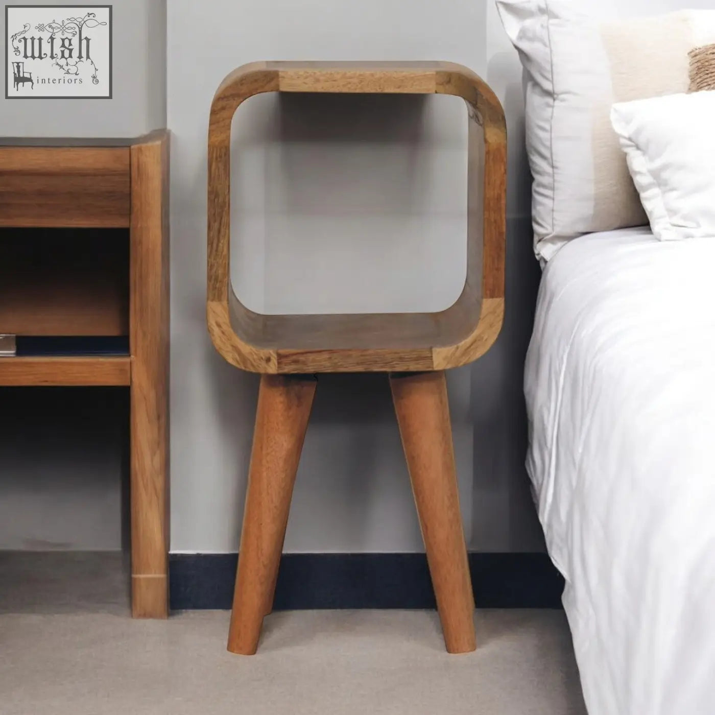 Extra mini minimalist open curved oak-ish bedside table with open shelf and three tapered legs in a wood finish