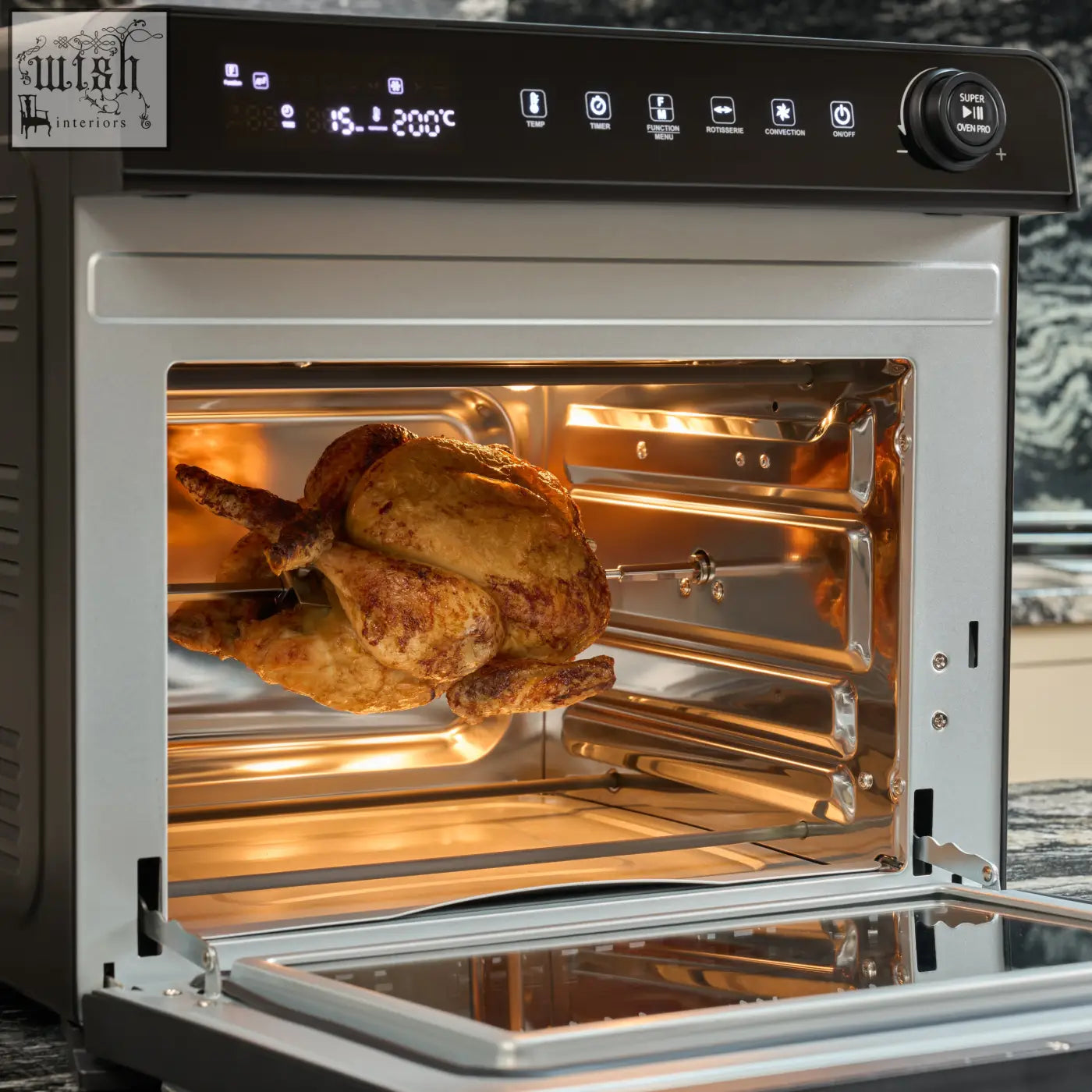 A golden brown roasted chicken spins on the rotisserie rod inside the silver stainless steel f77 super oven pro