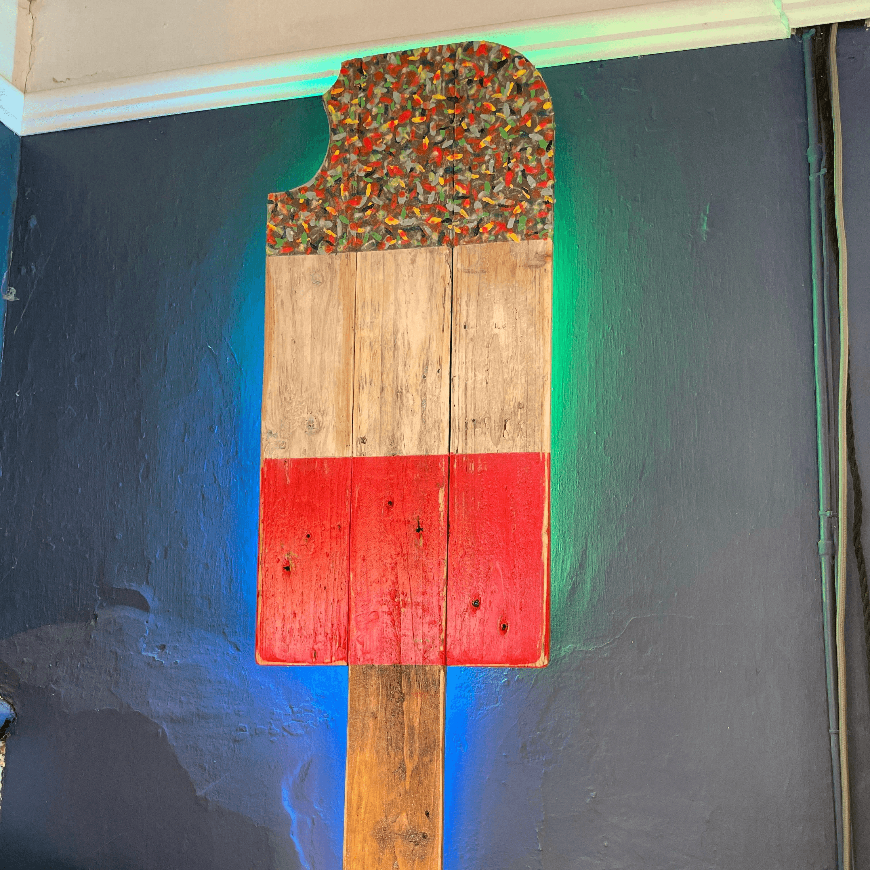 A rustic wooden fab lolly colour changing led wall light with colorful textured top and red painted lower section