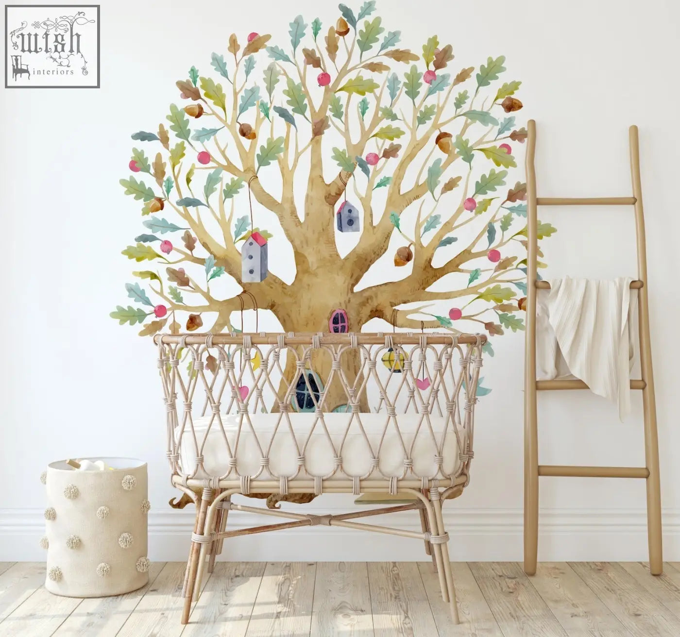 A woven rattan baby crib with cradle design and beige cushioning next to a fairy tree house wall decal in a magical garden