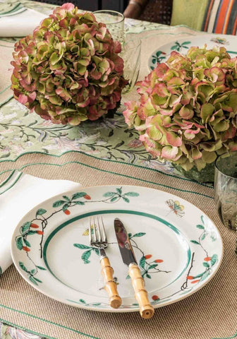 A white ceramic famille verte dinner plate with a green rim and hand painted botanical design set of 4