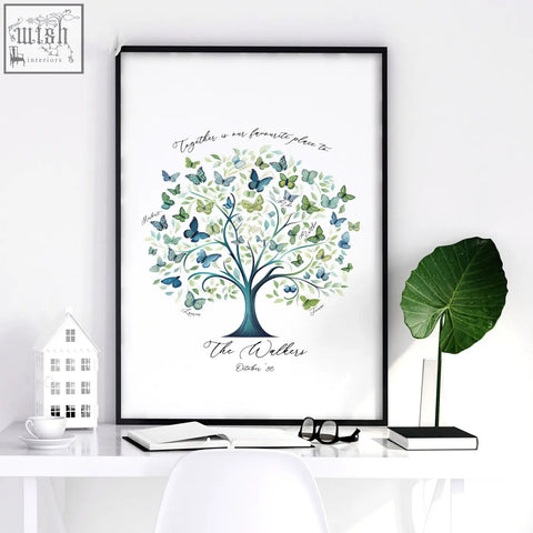 A framed family tree print with a blue-green trunk and watercolor leaves and butterflies in green teal and blue