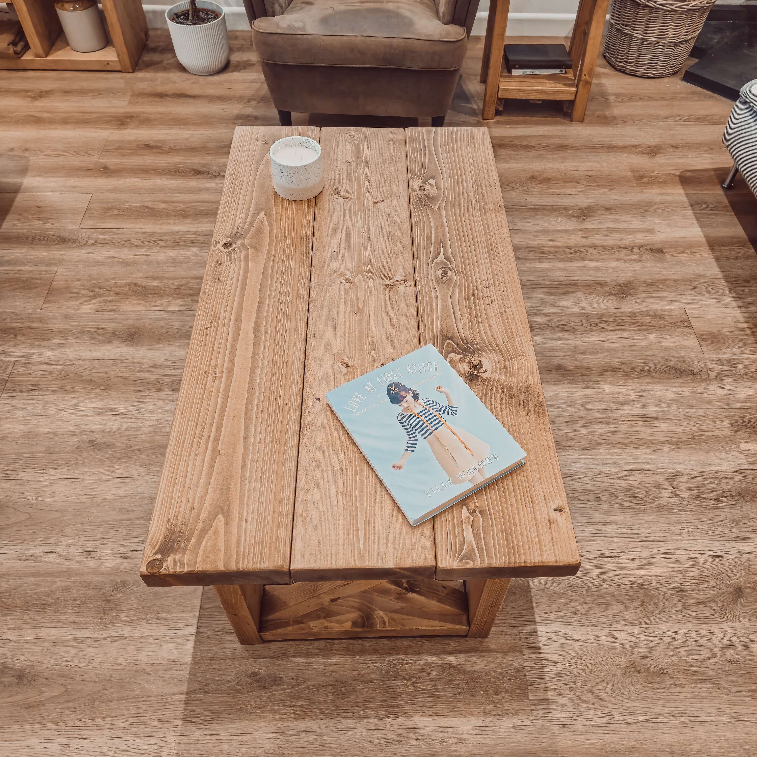 Rustic light brown farmhouse coffee table with visible wood grain natural knots and simple angled legs with shelf