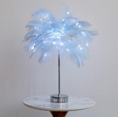 A delicate light blue feather lamp with a slender metallic stand and power supply perfect for modern bedside use