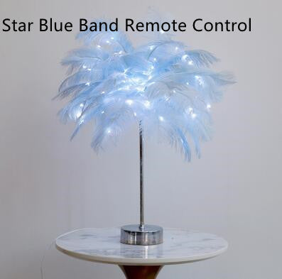A delicate light blue feather lamp with a slender metallic stand and circular base perfect as a modern table lamp