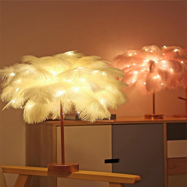 A delicate white feather lamp table lamp with warm glowing lights perfect as a nordic bedside decoration
