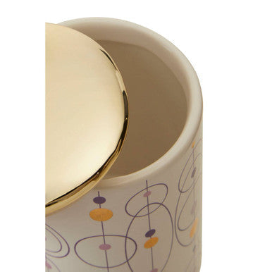 Cream-colored fenwick canister with gold finish lid featuring abstract geometric patterns in muted purple and mustard yellow