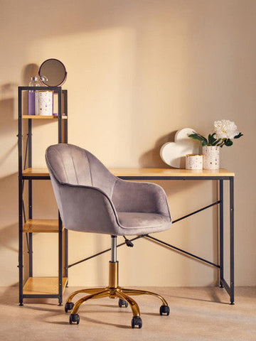 Gray velvet office chair with gold-tone base and casters next to fenwick canister with gold finish lid