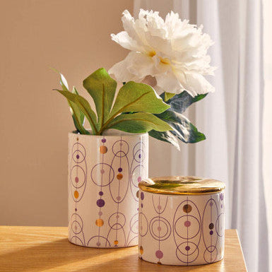 Cream-colored ceramic fenwick hair cosmetic brush holder with geometric purple gold and brown circular patterns