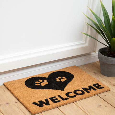 A tan coir filta paw heart doormat with a black heart, two paw prints, and bold welcome text