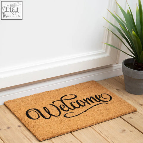 A tan coir doormat with black cursive welcome script perfect for outdoor use from filta welcome collection