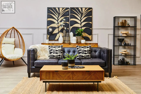 Black leather sofa with tufted upholstery and gold-tone nailhead trim next to fiori small succulent with natural stone base