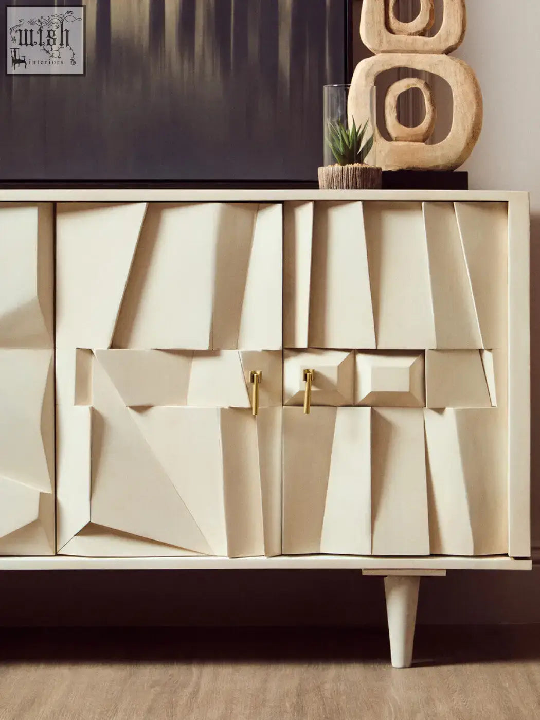 Cream-colored geometric sideboard with gold-tone handles and tapered legs beside fiori small succulent with natural stone base