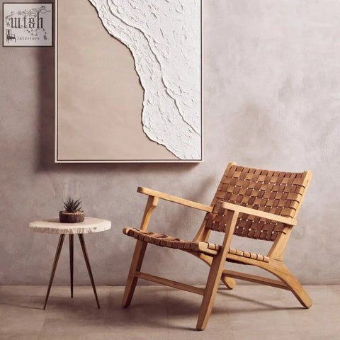 A woven leather armchair with a light wood frame next to a fiori small succulent with a natural stone base