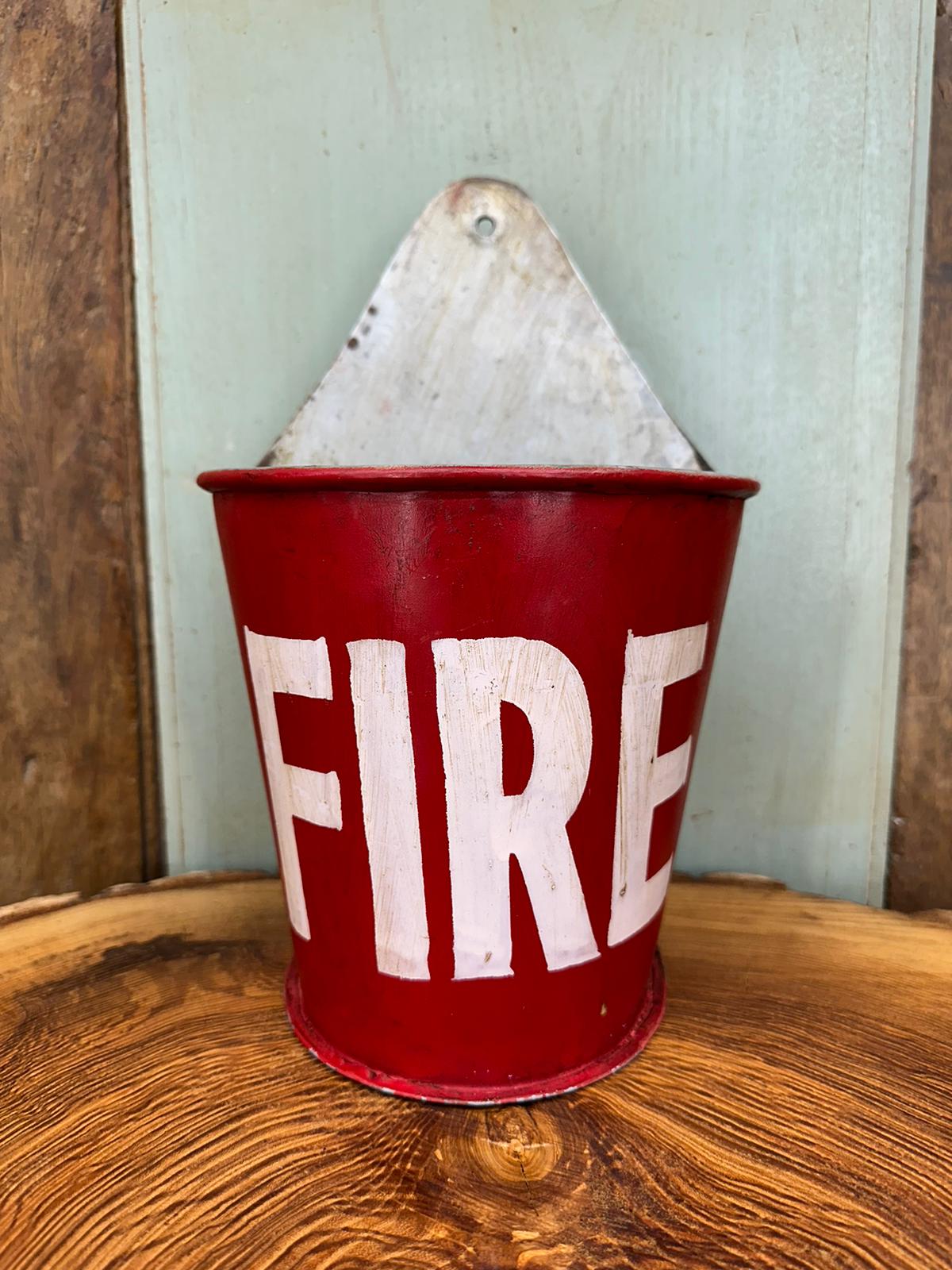 Red enamel fire plant pot with white fire lettering and weathered metal backplate shown from the back side
