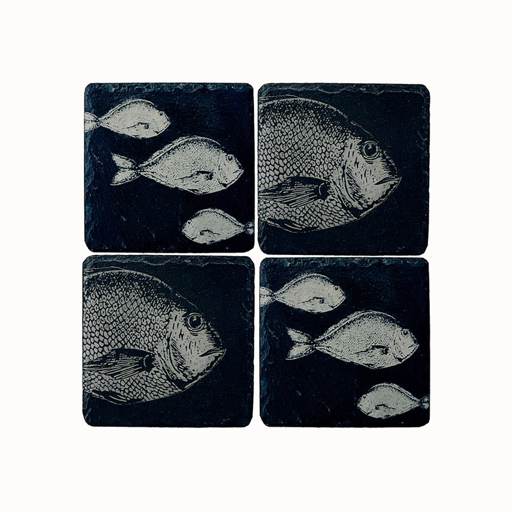 Set of four dark slate coasters with light gray engraved fish designs perfect for stylish drink protection