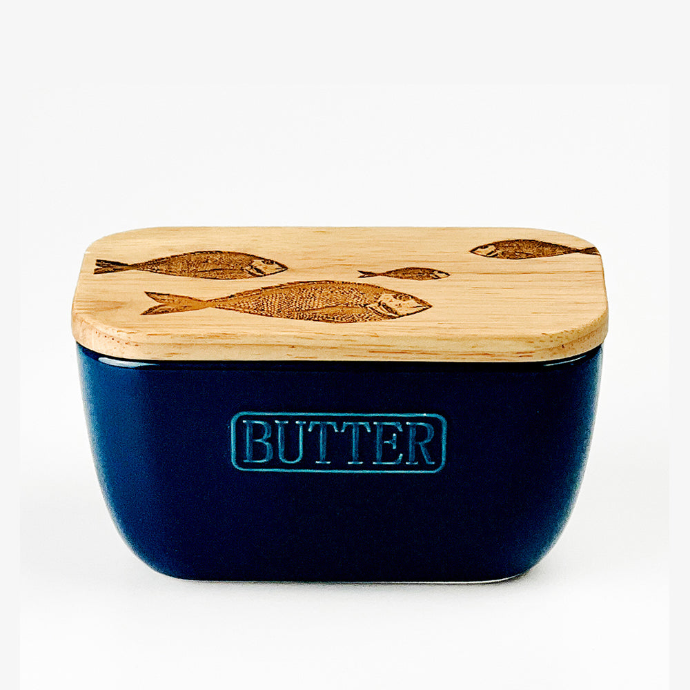 Navy blue ceramic fish repeat butter dish with a light wood lid engraved with fish designs and embossed butter text