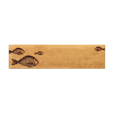 A rectangular oak serving platter with natural light brown finish and dark engraved fish designs