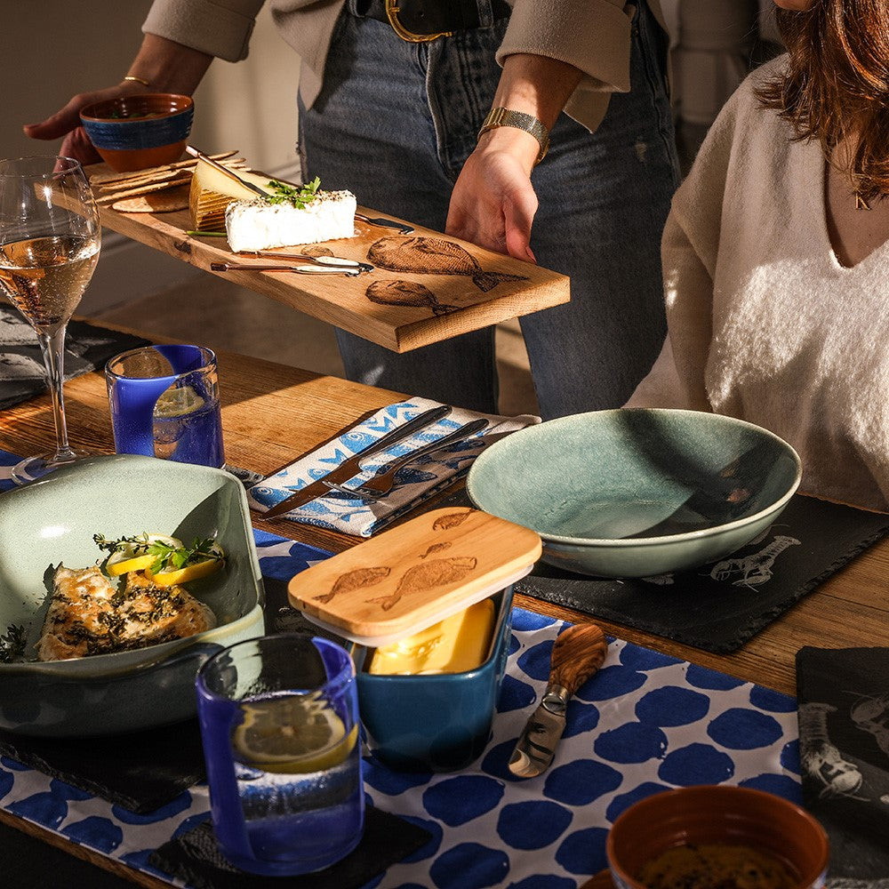 Wooden oak serving platter with engraved fish designs holding a block of cheese for stylish oak serving
