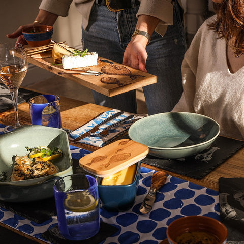 Wooden oak serving platter with engraved fish designs holding a block of cheese for stylish oak serving