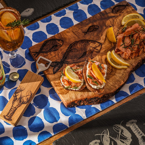 Natural olive wood chopping board with rustic engraved fish designs for serving and prep use