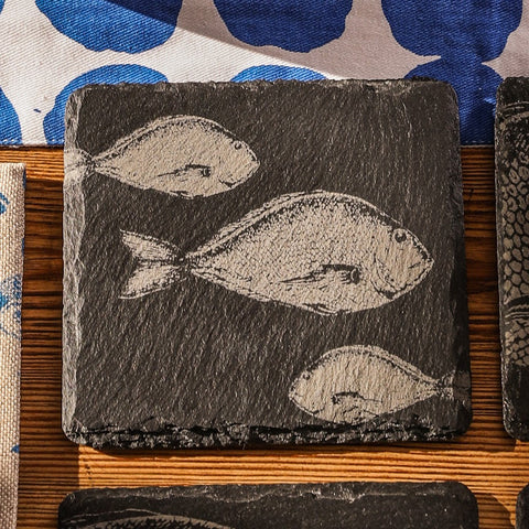Dark gray single slate coaster with hand carved light fish design perfect for drinks or decor use