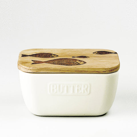 Cream-colored ceramic butter dish with natural wood lid featuring hand-carved fish repeat design