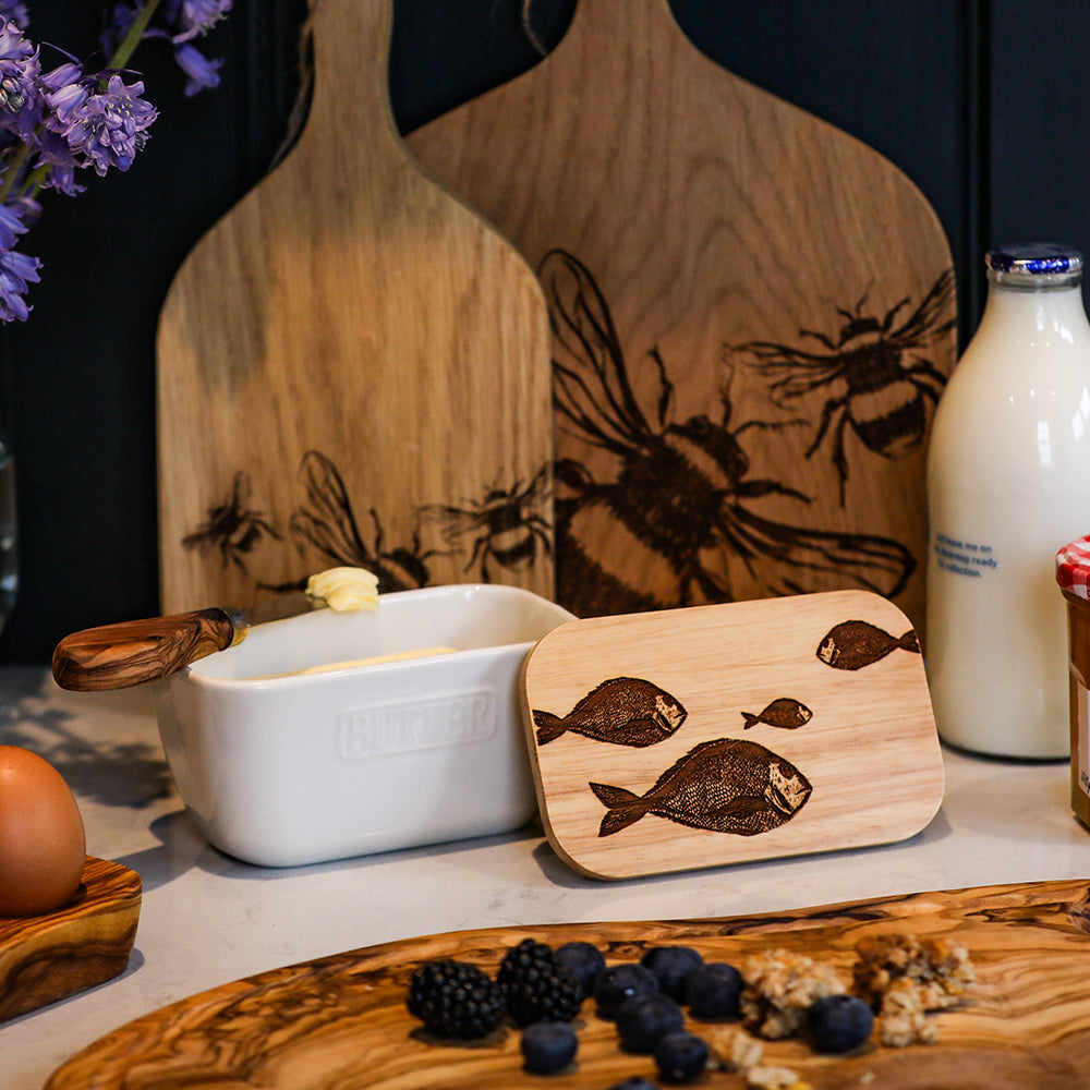 A light wood butter dish lid with dark brown laser engraved fish repeat designs for the fish repeat butter dish