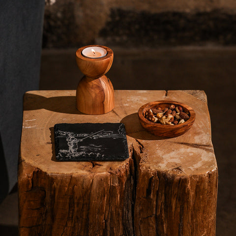 A rustic wooden candle holder with polished finish and natural wood grain alongside a fishing single slate coaster